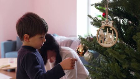 Téléchargez les photos : Mère et enfant décorant l'arbre de Noël avec des boules et des ornements. Préparation familiale pour les vacances d'hiver, célébration de la tradition - en image libre de droit