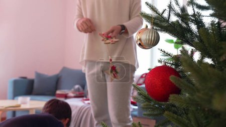 Téléchargez les photos : Mère et enfant décorant l'arbre de Noël avec des boules et des ornements. Préparation familiale pour les vacances d'hiver, célébration de la tradition - en image libre de droit