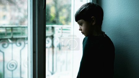 Foto de Un joven lucha con la enfermedad mental en casa con el color verde. Niño deprimido de pie por la ventana con expresión en blanco que representa una vida sin sentido - Imagen libre de derechos