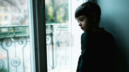 Foto de Un joven lucha con la enfermedad mental en casa con el color verde. Niño deprimido de pie por la ventana con expresión en blanco que representa una vida sin sentido - Imagen libre de derechos