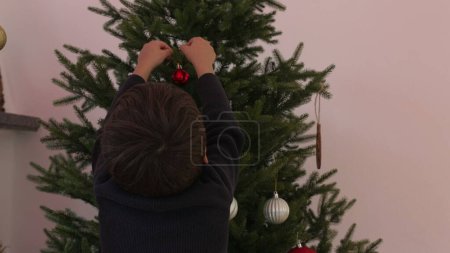Photo for Mother and child setting up Christmas tree, woman unboxing ball ornamention to decorate tree, child putting ornament, family preparing for winter holidays - Royalty Free Image