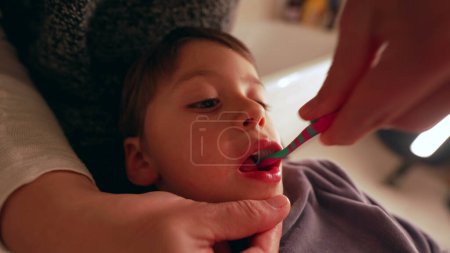 Téléchargez les photos : Gros plan sur le visage de l'enfant pendant que la mère se brosse les dents, hygiène dentaire la nuit avant le coucher, bouche du jeune garçon pendant l'hygiène dentaire - en image libre de droit