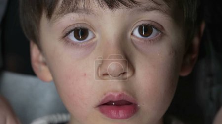 Foto de Cara de primer plano del niño mirando a la cámara capturada con lente macro. Retrato de niño - Imagen libre de derechos