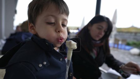 Foto de Niño enfriamiento caliente suizo Fondue, Comer en el restaurante al aire libre con mamá - Imagen libre de derechos