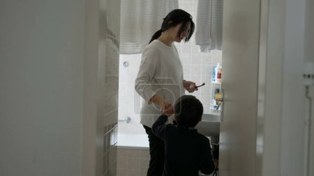 Photo for Candid mother and child standing in bathroom preparing to brush teeth together, domestic everyday lifestyle family activity, dental routine hygiene at home - Royalty Free Image