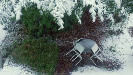 Téléchargez les photos : Saison de neige - vue sur la fenêtre de l'appartement de la cour couverte de truie, chaises reposant sur la table - en image libre de droit