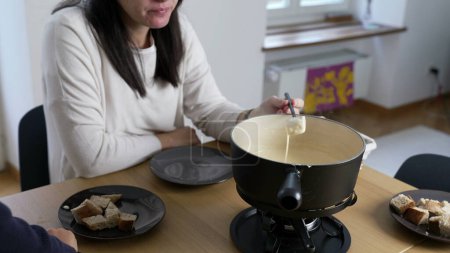 Photo for Swiss Fondue Feast, woman Enjoying Bread and Cheese at Home. homemade traditional European dish in Switzerland - Royalty Free Image
