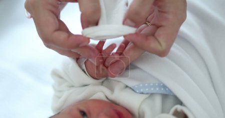 Foto de Mother putting small glove into newborn baby infant - Imagen libre de derechos