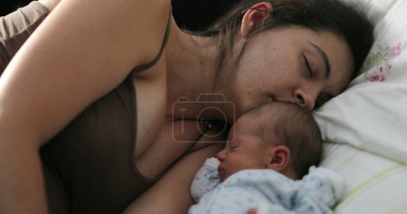 Téléchargez les photos : Candid family moment of mother and newborn asleep in bed - en image libre de droit