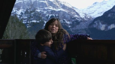 Téléchargez les photos : Jeunes frères et sœurs embrassant le chalet Balcon pour la photo dans les Alpes, petit frère embrassant sœur, amour et affection de la famille - en image libre de droit