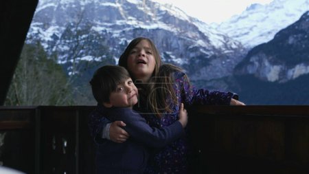 Photo for Young Siblings Embracing on Chalet Balcony for Photo in the Alps, small brother hugging sister, family love and affection - Royalty Free Image