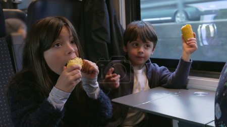 Photo for Siblings Snacking Corn in Moving Train - Brother and Sister Enjoying Healthy Food - Royalty Free Image