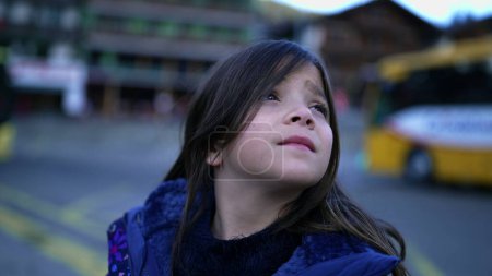 Foto de Portrait of a happy small girl chuckling at camera standing in urban setting. Closeup face of child wearing blue jacket - Imagen libre de derechos
