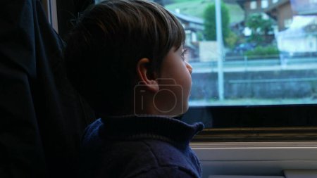Photo for One small boy traveling by train looking at scenery pass by while eating corn. Child snacking healthy food and pointing at view from high speed transportation - Royalty Free Image