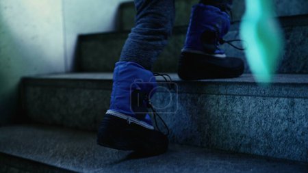 Téléchargez les photos : Enfant en bottes de pluie Escaliers d'escalade, prêt pour la pluie - en image libre de droit