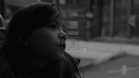 Foto de Passenger child travels by bus looking at scenery pass by in black and white, monochromatic clip of thoughtful small girl - Imagen libre de derechos