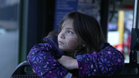 Foto de Kids inside bus, little girl leaning on passenger seat grabbing pillow traveling with family, authentic real life lifestyle scene - Imagen libre de derechos