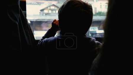 Foto de Back of pensive child observing view from train stopped at platform station. Kid traveling and daydreaming, lost in thought - Imagen libre de derechos