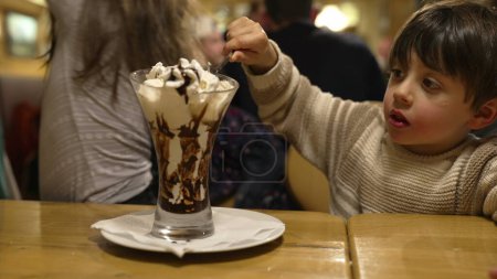 Photo for Little Brother and Sister Enjoying Ice Cream Sundae with Whipped Cream - Family Weekend Outing at Restaurant Diner - Royalty Free Image