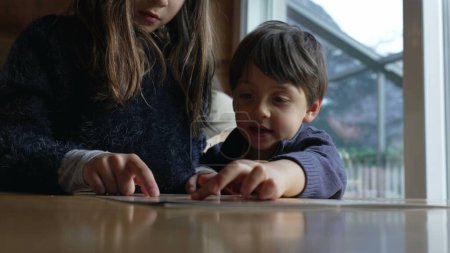 Téléchargez les photos : Enfants au restaurant cueillette de la nourriture à partir du menu, petite fille de 8 ans pointant vers l'option à côté de son frère - en image libre de droit