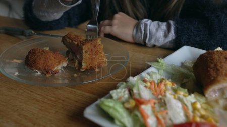 Téléchargez les photos : Enfants dégustant de la nourriture au restaurant, petite fille mangeant de la viande milanaise avec des frites. Enfants au dîner pendant l'heure du déjeuner - en image libre de droit