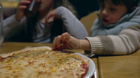Téléchargez les photos : Des enfants attrapant une part de pizza au restaurant, des frères et sœurs sur le point de manger des glucides au restaurant. Petite fille mangeant de la pizza - en image libre de droit