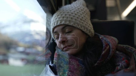 Téléchargez les photos : Femme qui s'endort en voyageant en train. Passager femelle penché sur la fenêtre ferme les yeux tout en voyageant en mouvement - en image libre de droit