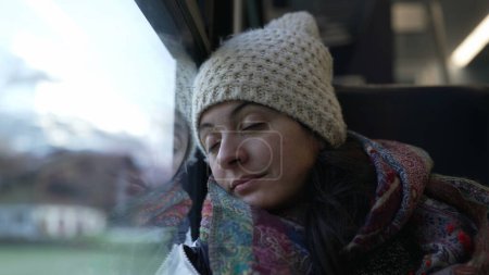 Photo for Woman falling asleep while traveling by train. Female passenger leaning on window closes eyes while traveling in motion - Royalty Free Image