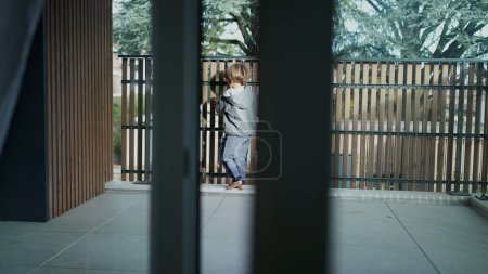 Foto de Niño corriendo en apartamento terraza balcón apoyado en ventana de cristal - Imagen libre de derechos