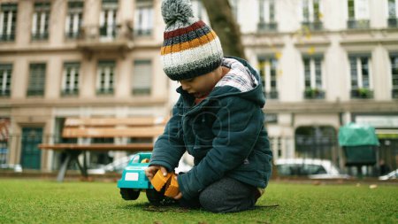 Téléchargez les photos : Un enfant en jeu dans le parc d'automne - Un tout-petit jouit d'un camion-jouet le jour du froid - en image libre de droit