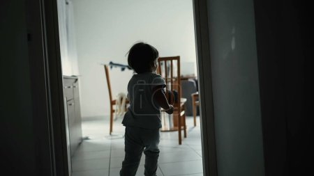 Photo for Back View of Child Running Indoors - Young Boy Sprinting Inside Apartment captured in slow-motion. Carefree kid having fun diving into sofa couch at apartment - Royalty Free Image