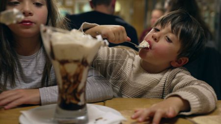 Foto de Los niños disfrutando de helados con crema batida. hermano y hermana disfrutan del postre - Imagen libre de derechos