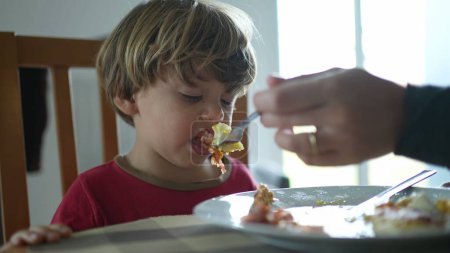 Foto de Un niño escupiendo comida durante el almuerzo. Niño no queriendo comida, sintiendo asco - Imagen libre de derechos
