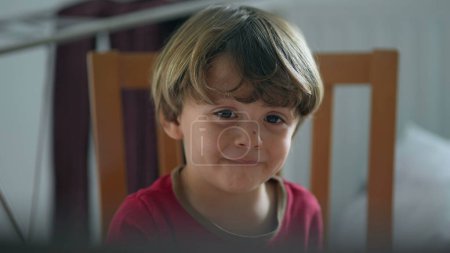 Téléchargez les photos : Gros plan visage d'enfant regardant la télévision hypnotisée par le contenu des médias en ligne. Un petit garçon caucasien enfant fixe l'écran - en image libre de droit