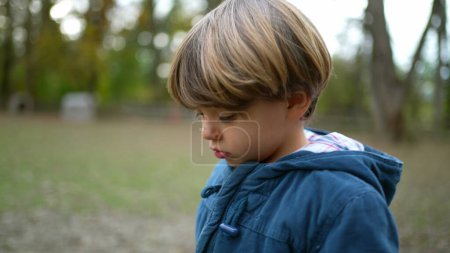 Photo for Pensive thoughtful little boy walking outside in nature daydreaming. 4 year old introspective Child walks forward at forest park - Royalty Free Image