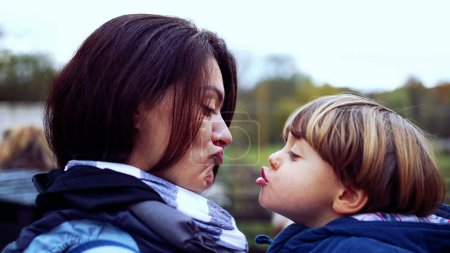 Photo for Mother and child peck kiss in authentic caring parent and child relationship. mom holding small son in arms - Royalty Free Image