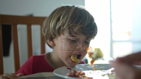 Foto de Un niño escupiendo comida durante el almuerzo. Niño no queriendo comida, sintiendo asco - Imagen libre de derechos