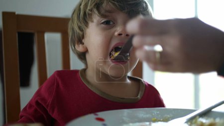 Foto de Primer plano niño que se alimenta de alimentos durante la hora del almuerzo. Alimentación de los padres pequeño niño alimento nutritivo - Imagen libre de derechos