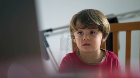 Foto de Primer plano del niño pequeño hipnotizado por la pantalla, el niño mirando intencionadamente el contenido de los medios de televisión - Imagen libre de derechos