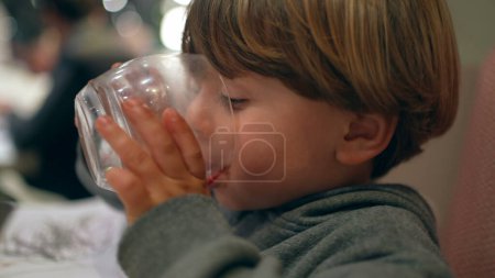 Photo for Child Quenching Thirst with Water After Meal - Hydration at Restaurant - Royalty Free Image