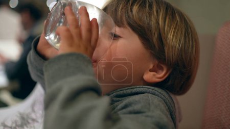 Photo for Child Quenching Thirst with Water After Meal - Hydration at Restaurant - Royalty Free Image