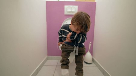Téléchargez les photos : Enfant pensif assis aux toilettes de la salle de bain. Garçon de 3 ans faisant ses besoins dans les toilettes - en image libre de droit