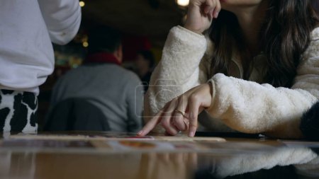 Téléchargez les photos : Main de femme cueillette de la nourriture à partir du menu du restaurant parler avec le serveur et montrant l'option, doigt pointant vers l'image de sélection de nourriture - en image libre de droit
