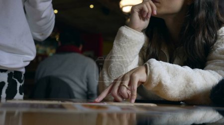Téléchargez les photos : Main de femme cueillette de la nourriture à partir du menu du restaurant parler avec le serveur et montrant l'option, doigt pointant vers l'image de sélection de nourriture - en image libre de droit