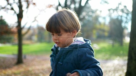 Photo for Boy Walking in Autumnal Park - Toddler Amidst Colorful Leaves on Sunny Day - Royalty Free Image