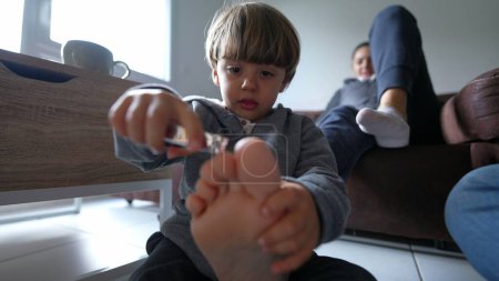 Photo for Playful Child and Mother's Pedicure Time at Home, little boy attempts to trim reluctant parent, closeup toes and feet while kid holds for trimming, fun lifestyle moment - Royalty Free Image