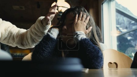 Foto de Cansada niña aburrida cubriendo la cara con las manos en la cafetería del restaurante, triste niño se siente agotado y aburrimiento - Imagen libre de derechos