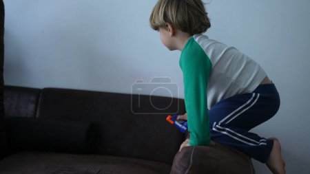 Photo for Child climbing on top of the edge of a sofa couch at home - Royalty Free Image