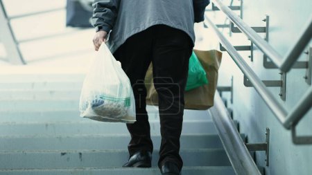 Foto de Persona que lleva víveres por las escaleras desde el tren subterráneo. Viajeros diarios con comestibles Escaleras ascendentes desde el metro - Imagen libre de derechos