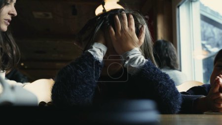 Foto de Cansada niña aburrida cubriendo la cara con las manos en la cafetería del restaurante, triste niño se siente agotado y aburrimiento - Imagen libre de derechos